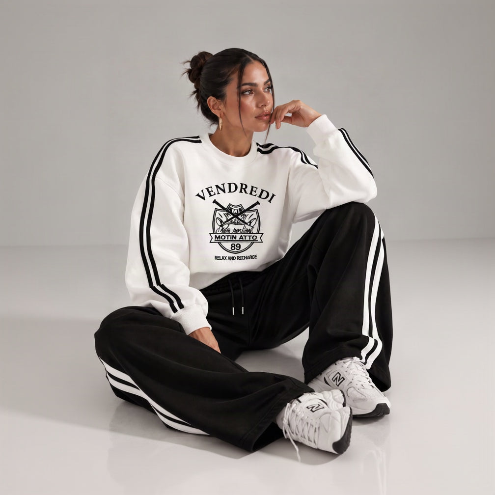 Woman in a white varsity print sweatshirt with black sleeve stripes and black striped wide leg pants
