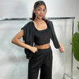 Woman in a black velvet zip jacket slipped off the shoulders over a matching crop top and pants