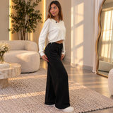 Side view of black wide leg sweatpants with a relaxed straight fall, worn with white trainers