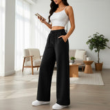Woman wearing black wide leg sweatpants with a drawstring waist indoors