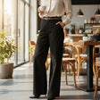 Person wearing a white blouse and black pants in a modern cafe setting