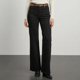 Person wearing black wide-leg pants with a brown belt on a white background