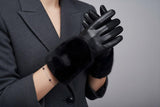 Person wearing black leather gloves with a grey background