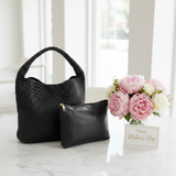 Black woven handbag and clutch with pink flowers and 'Happy Mother's Day' card on marble surface