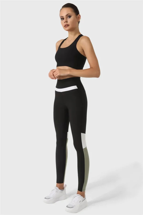 Woman wearing a black athletic outfit with white accents on a white background
