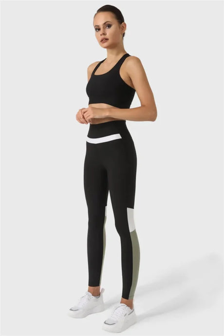 Woman wearing a black athletic outfit with white accents on a white background