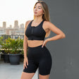 Woman in black athletic wear standing on a rooftop with city skyline in the background