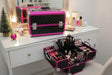 Black quilted aluminium vanity cases with fuchsia trim, one open with loaded trays