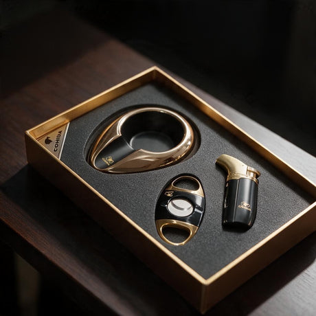 Gold and black cigar ashtray with a black and gold cutter and torch lighter in a gold edged box