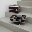 Black quilted aluminium vanity cases with baby pink trim, one open with makeup trays