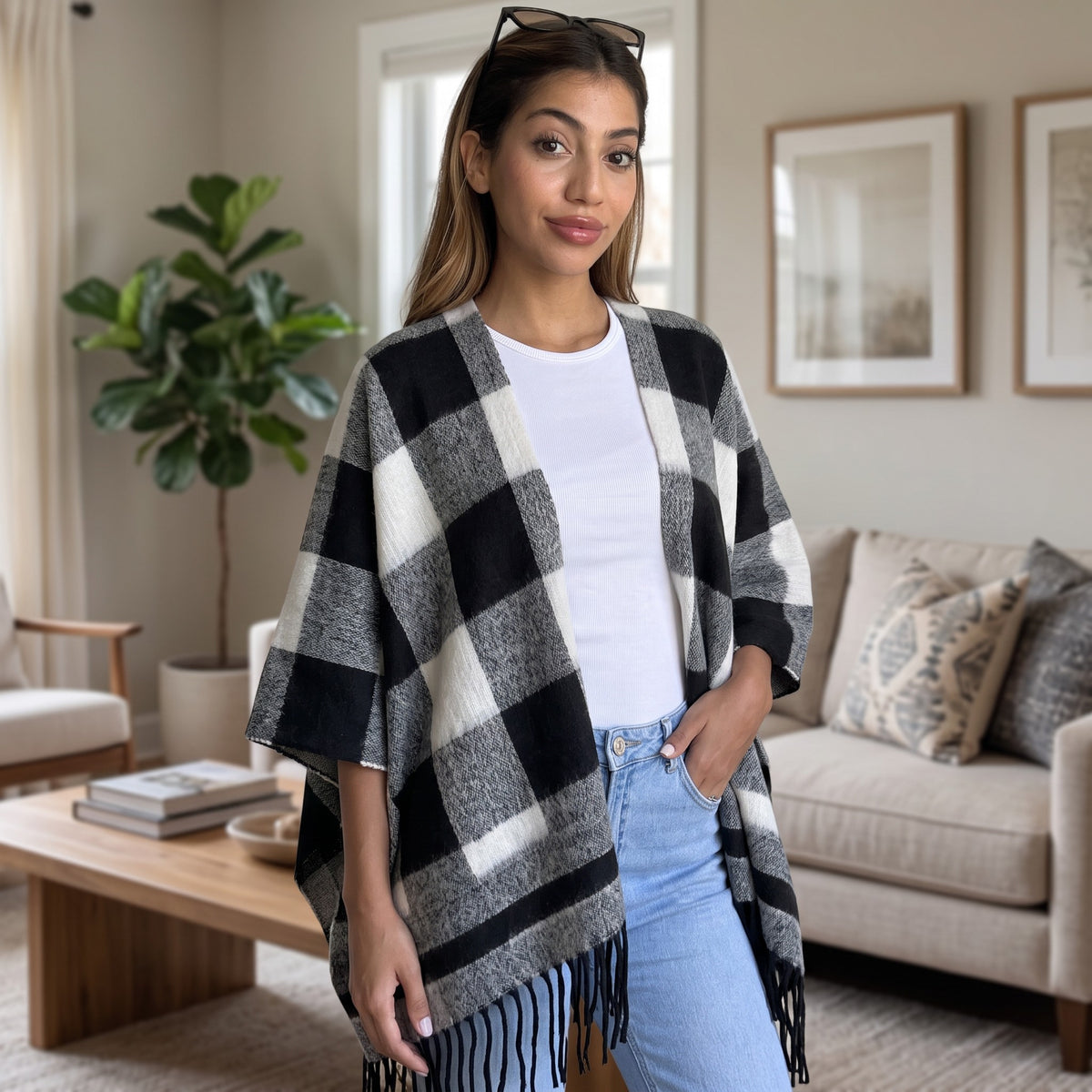 Woman wearing an open front black and white check poncho with fringed hem over jeans