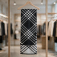 Black scarf with a white check pattern folded over a hanger, its white reverse side showing below