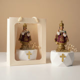 Two Infant of Prague figures, one bagged and one standing on its faceted white base