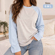 Woman in a heather grey long sleeve top with light blue raglan sleeves and jeans