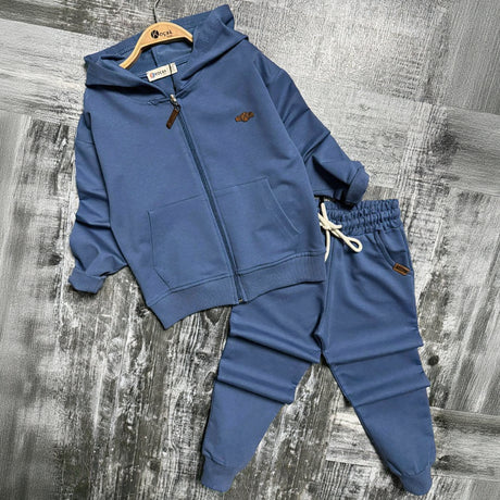Blue zip up hooded jacket with front pockets and matching cuffed joggers on a grey backdrop