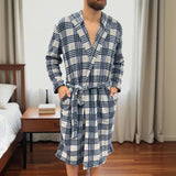 Blue checkered fleece robe worn standing beside a bed, belt tied at the waist