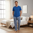 Blue checkered pyjama set worn standing by a lit fireplace at night