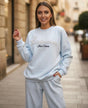 Woman wearing a light blue sweatshirt and sweatpants on an urban street