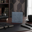 Blue leather wallet on a desk with books, glasses, and a cup in the background