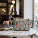 Blue floral tapestry crossbody bag with a gold chain on a marble table
