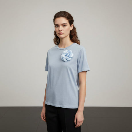 Woman wearing a blue tshirt with a floral design on a plain background