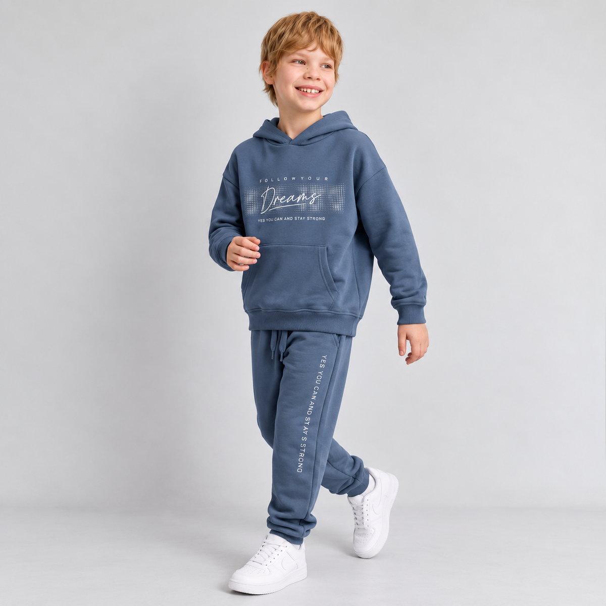 Smiling boy in a blue Follow Your Dreams hoodie and matching joggers