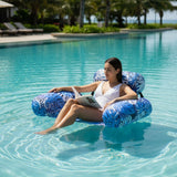 Woman relaxing on a blue leaf print inflatable pool chair