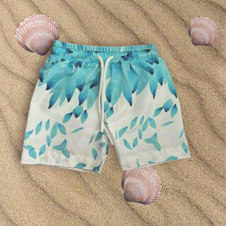 Blue leaf-patterned shorts on sand with shells