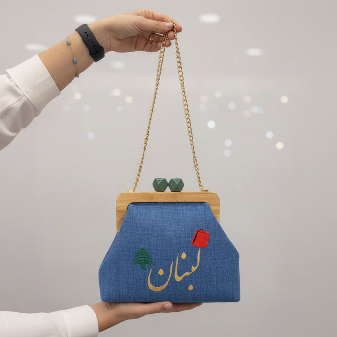 Denim Lebanon bag held in two hands to show its size and gold chain strap