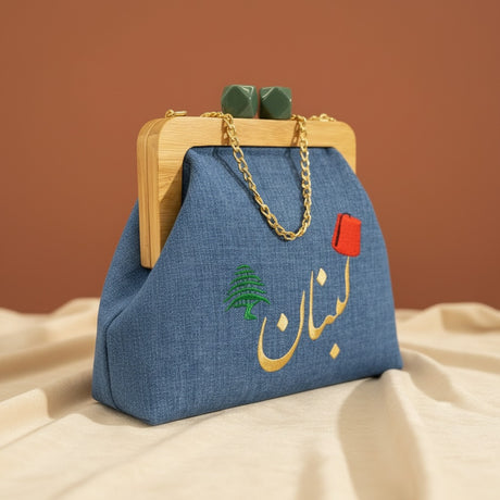 Denim frame bag with sage green ball clasps, a green cedar and gold Arabic lettering