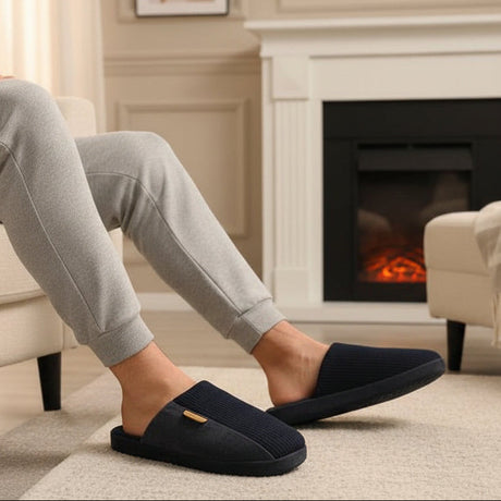 Person wearing navy blue slippers in a cozy living room with a fireplace