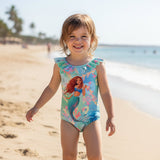 Toddler wearing a blue mermaid print onepiece swimsuit on the beach