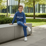 Boy seated outdoors in a blue long sleeve New York top and blue joggers, two piece set