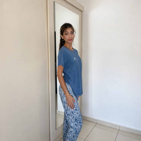 Side profile of a blue sleepwear top over floral paisley trousers