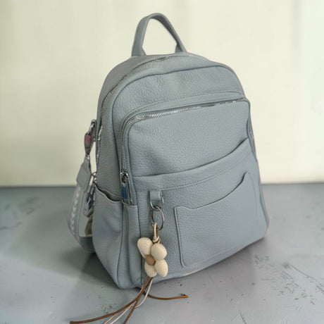 Pale grey blue backpack shown from the side with the shoulder strap visible