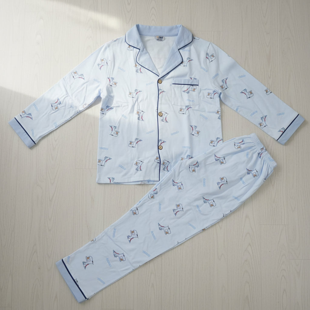 Light blue cartoon dinosaur print button front kids pyjama set laid flat on a wood floor