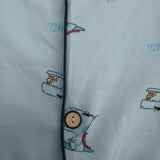 Button placket close up with navy piping and cartoon dinosaur print on light blue pyjama fabric