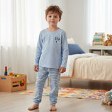 Boy in a light blue pyjama top with sailboat motif and striped pants