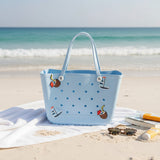 Blue polka dot beach bag with decorative elements on a sandy beach.