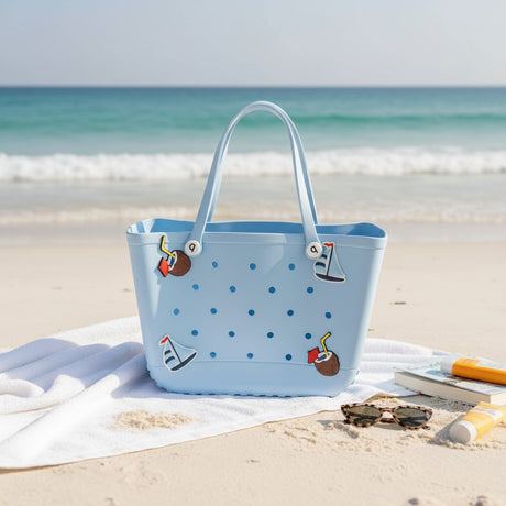 Blue polka dot beach bag with decorative elements on a sandy beach.