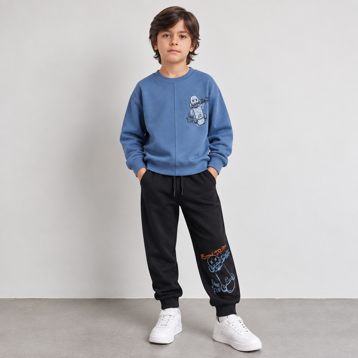 Boy in a blue skateboard sweatshirt and black printed joggers, front view