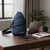 Blue Calvin Klein sling bag on a desk with a laptop and office supplies