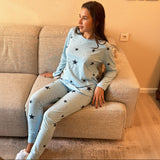 Woman relaxing on a beige couch wearing a light blue star print pyjama set