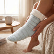 Pale blue knit slipper socks with silver stripes and a folded white sherpa cuff