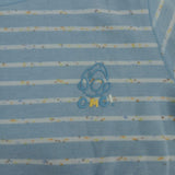 Close up of light blue stripe pyjama fabric with confetti flecks and a small outlined chest motif