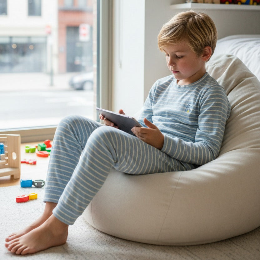 Boy in a light blue striped pajama set on a bean bag