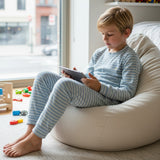 Boy in a light blue striped pajama set on a bean bag