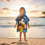 Boy on the beach in a blue Mickey Mouse poncho towel with a surfing print