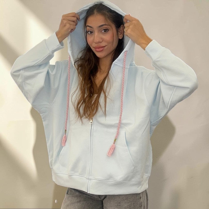 Hood raised on the pale blue hoodie, showing the ribbed cuffs and roomy sleeves