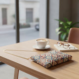 Tile pattern tapestry bag resting on a table by a window